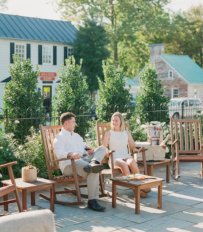 Couple enjoying a sunny day on a patio with wooden rocking chairs